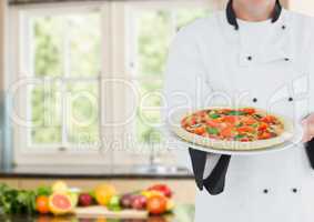 Chef with pizza against blurry kitchen with vegetables
