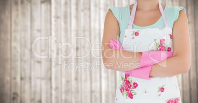 Woman in apron with arms folded against blurry wood panel