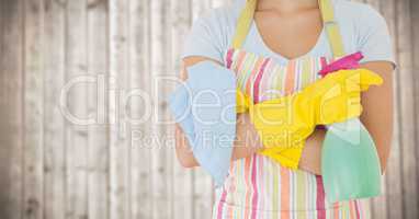 Woman in apron with cleaner against blurry wood panel