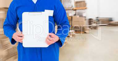 Mechanic holding up clipboard against blurry boxes