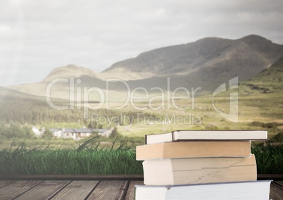 Books stacked by landscape mountains