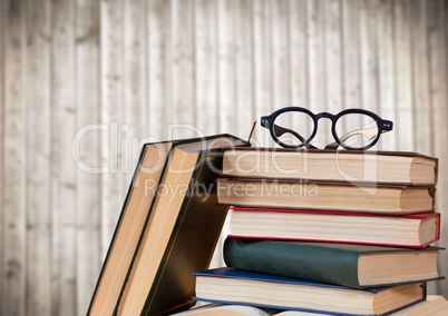 Pile of books and glasses against blurry wood panel