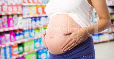 Pregnant woman mid section in blurry grocery store