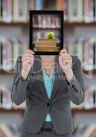 Business woman with tablet showing book pile with green apple against blurry bookshelf