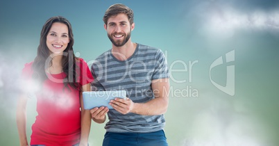 Couple with tablet against blue green background with clouds