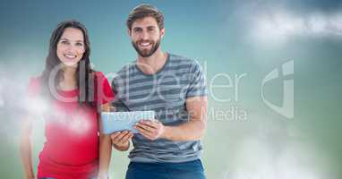 Couple with tablet against blue green background with clouds