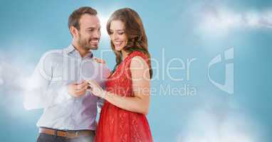 Couple engaged against blue background with clouds