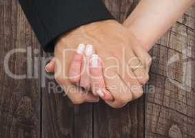 Wedding couple holding hands against wood
