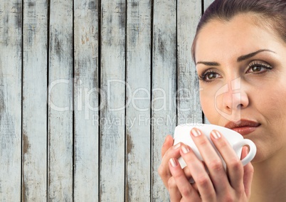 Close up of woman drinking from white cup against wood panel