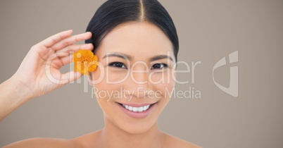 Woman with yellow flower in hair against brown background