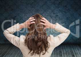 Stressed woman holding head by blue wall