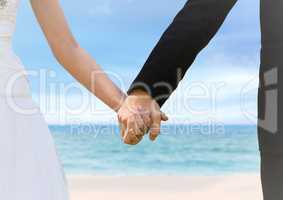 Bride and groom holding hands at blurry beach