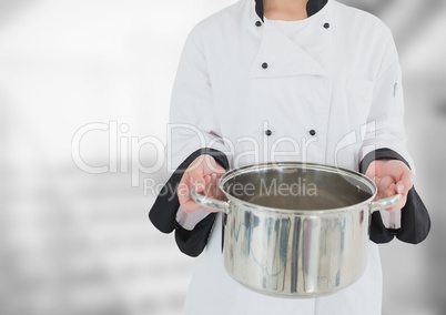 Chef with saucepan against blurry grey stairs