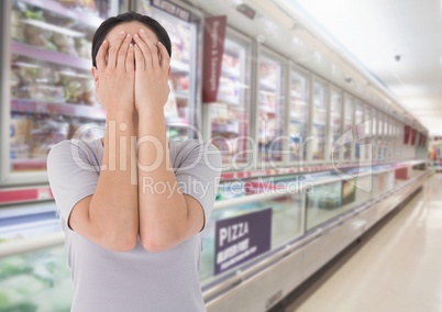 Sad woman grief hands over face against supermarket background