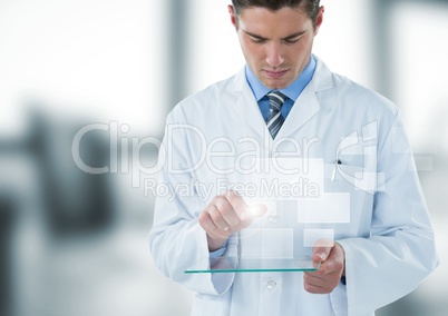 Man in lab coat looking down at glass device and square interface against blurry window