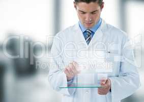 Man in lab coat looking down at glass device and square interface against blurry window
