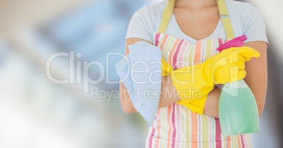 Woman in apron with cleaner against blurry window