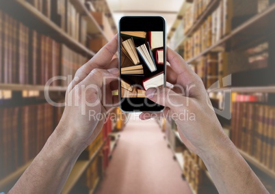 Hand with phone showing standing books against blurry bookshelves