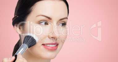 Woman with make up brush against pink background