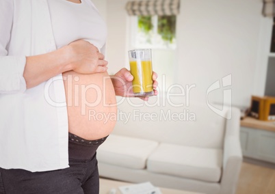 Pregnant woman mid section holding orange juice in blurry sitting room