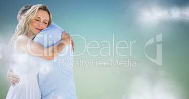Couple hugging against blue green background with clouds