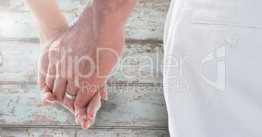 Wedding couple holding hands against wood