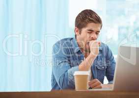 Man with laptop and coffee against blurry blue window