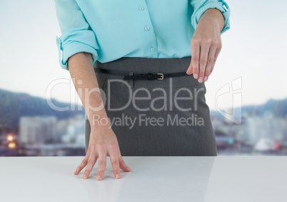 Business woman mid section at desk against blurry skyline