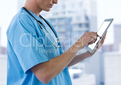 Nurse mid section with tablet against blurry buildings