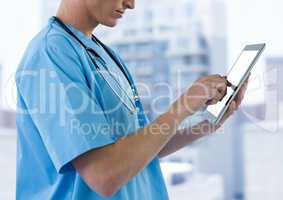 Nurse mid section with tablet against blurry buildings