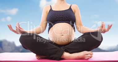 Pregnant woman Meditating against mountain