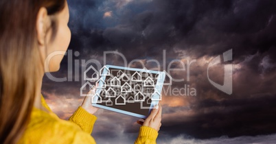 Woman over shoulder with tablet and white house graphics against stormy sky