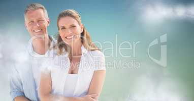 Couple smiling against blue green background with clouds
