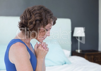Woman praying hopeful and sad next to bed