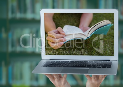 Hands with laptop showing book on grass against blurry bookshelf with green overlay