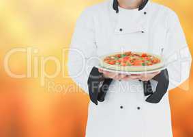 Chef with pizza against blurry orange background