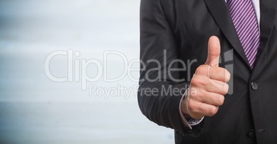 Business man mid section giving thumbs up against blurry grey wood panel