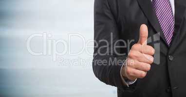 Business man mid section giving thumbs up against blurry grey wood panel