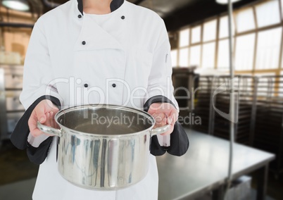 Chef with saucepan against blurry kitchen