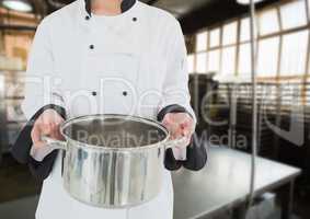 Chef with saucepan against blurry kitchen