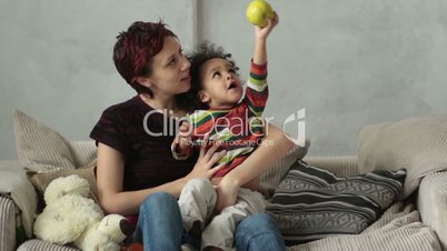 Mother playing with mixed race toddler son on sofa