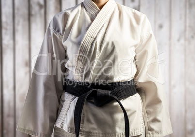 Woman in karate suit mid section against blurry wood panel
