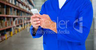 Mechanic holding up phone against blurry warehouse