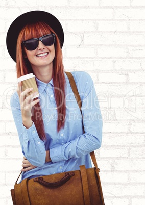 Woman with coffee cup and bag against white brick wall