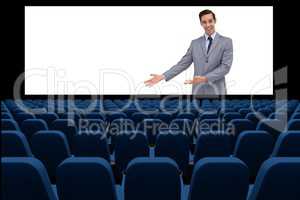 Businessman on screen presenting at blank  in front of 3d empty chairs