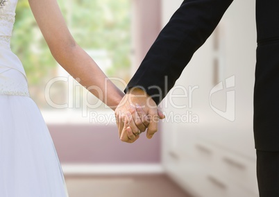 Wedding couple holding hands near window