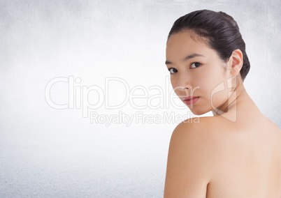 Woman looking over shoulder against white wall