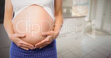 Pregnant woman mid section in blurry kitchen