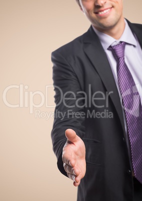 Business man with hand outstretched against cream background