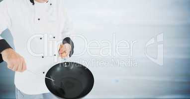 Chef with wok against blurry grey wood panel